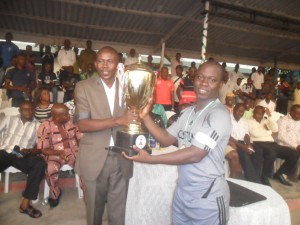 The representative of the Commissioner of Sports presenting the trophy to the captain of Team Customs, winners of the maiden edition of the Cross River State Security Unity Cup