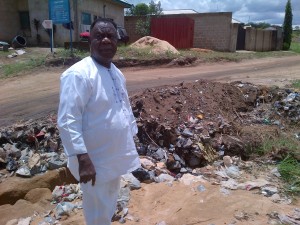 Dr. Okpo Ojah, veteran journalist and a research fellow in University of Calabar pointing to a failed portion of Ikot Omin road