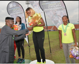 Cross River State Governor, Senator Liyel Imoke decorating  Blessing Okagbare with the Gold medal/ bouquet of flower as she emerged champion in the women's 100mtrs  finals finishing at 11.06  during the ongoing Cross River/All Nigerian Athletics Championship 2014..Finishing in second place with 11.17 2nd is Gloria Asumnu also of Delta state and in 3rd place is Sule Justina 11.65 seconds in Calabar