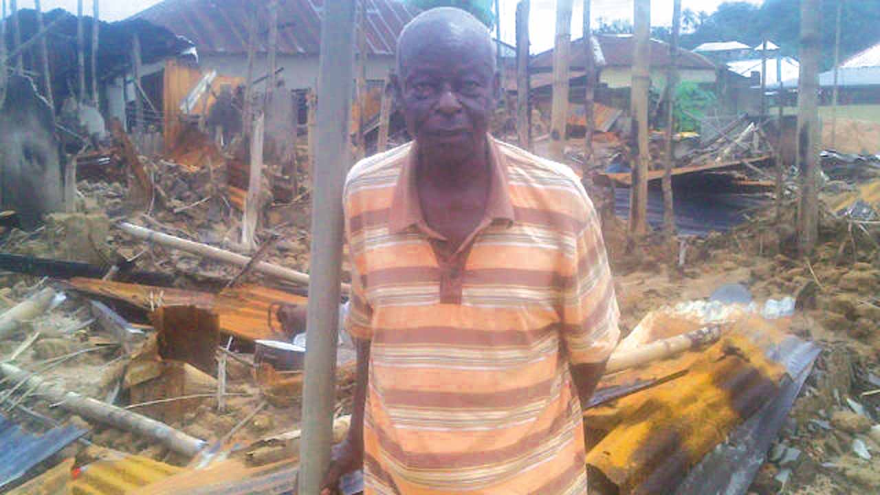 Chief Bassey in front of his burnt house