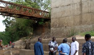 The CRS Commissioner for Works, Pius Ankpo (2L) and his counterpart in Education (in white) interact with locals and an engineer at the base of the old and new Akreha bridge under construction while users look on. (30/3/2024)